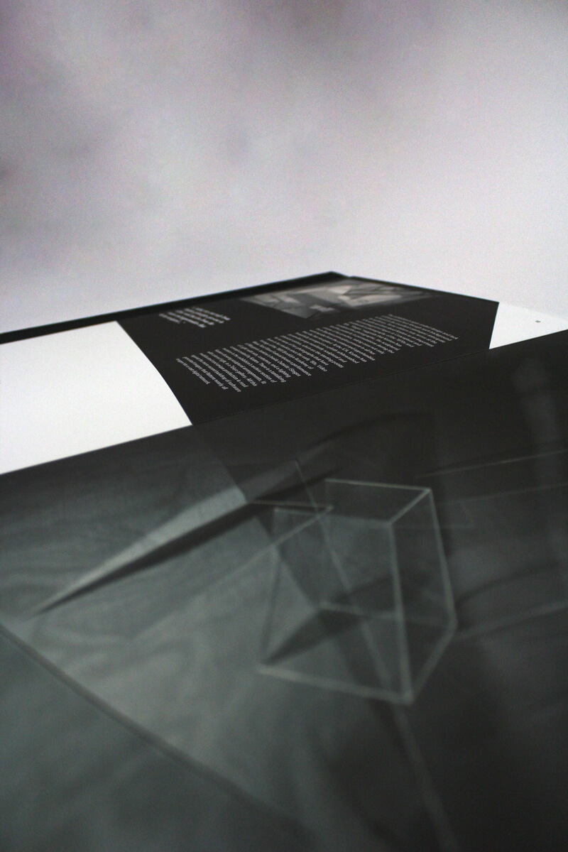 Closeup of artist book of Barbara Kasten featuring two photos of her sculptures playing with light through clear boxes.