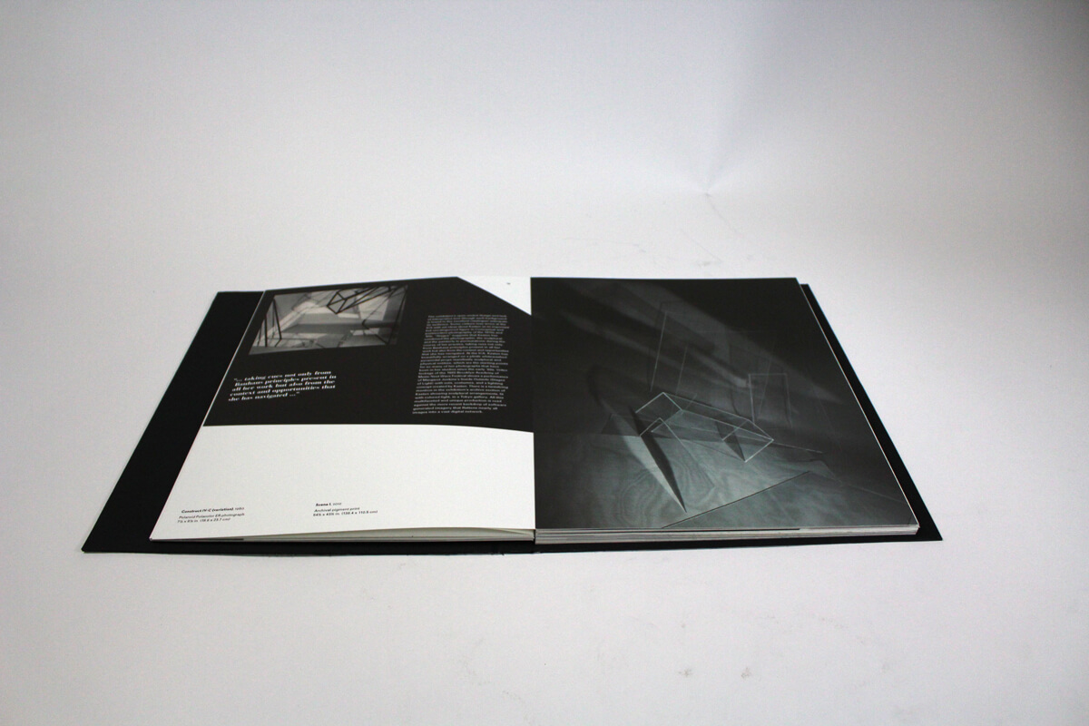 Spread of artist book of Barbara Kasten featuring two photos of her sculptures playing with light through clear boxes.